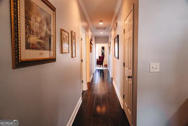 a view of a hallway with wooden floor and a painting on the wall
