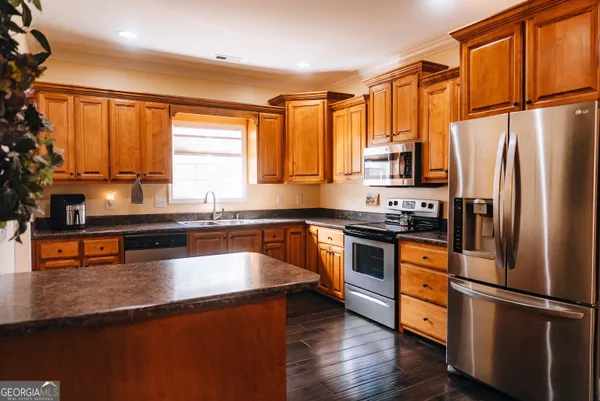 a kitchen with stainless steel appliances granite countertop a refrigerator a sink dishwasher a stove and white countertops with wooden floor