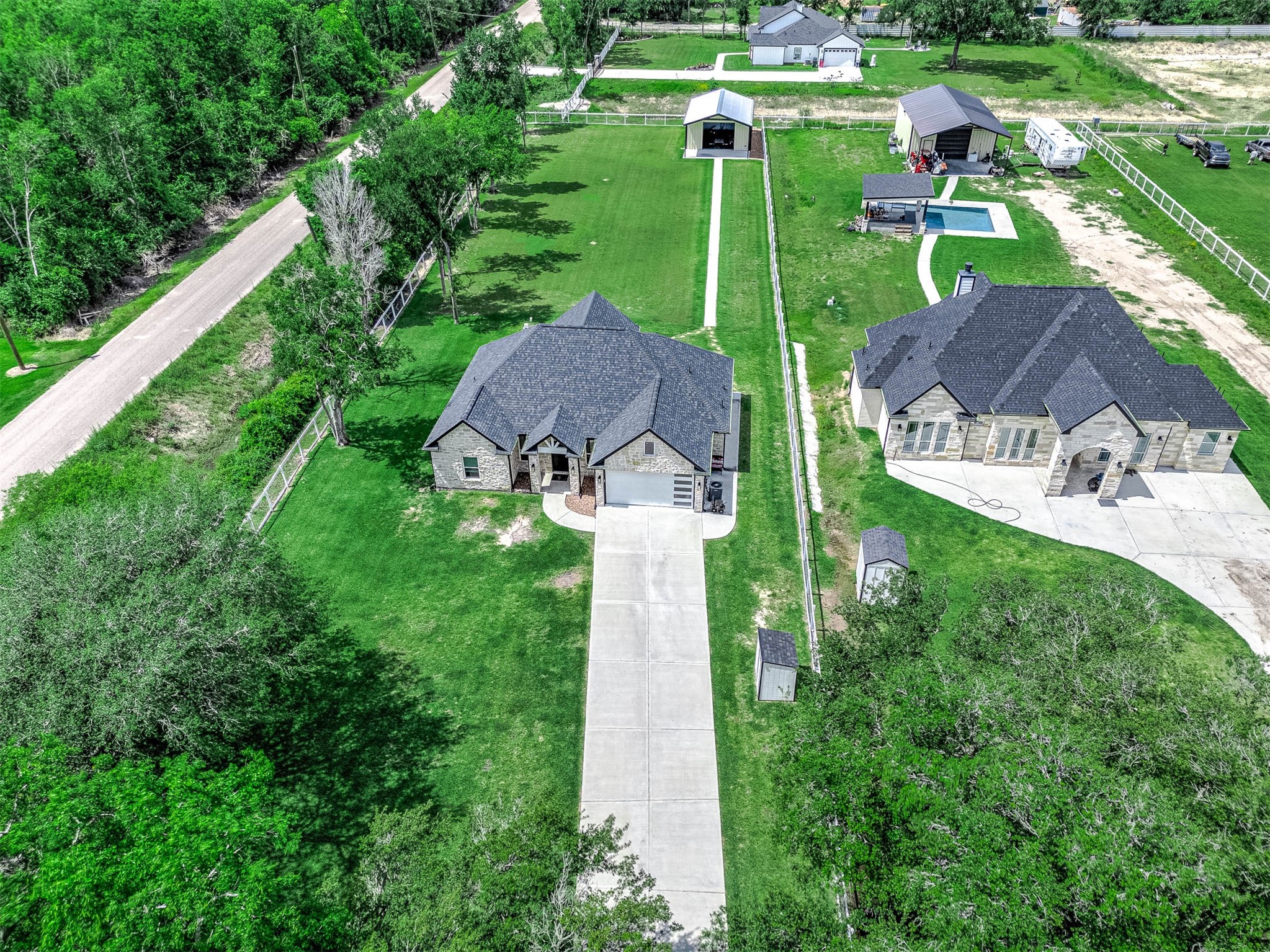 8032 Short Road Needville, TX 77461 - Photo 47 of 50 This aerial perspective showcases the property’s spacious layout, including the long driveway, expansive outdoor space, additional structures, and backyard pool area. The combination of open land and thoughtful improvements creates a private setting with plenty of room for entertaining, recreation, and everyday enjoyment.