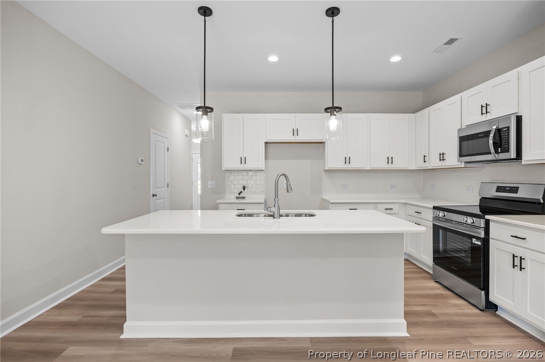 232 Elijah Way, Unit 8 Vass, NC 28394 - Photo 12 of 41 a kitchen with kitchen island a sink stainless steel appliances and cabinets