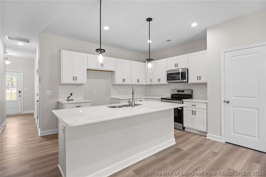 232 Elijah Way, Unit 8 Vass, NC 28394 - Photo 13 of 41 a kitchen with stainless steel appliances granite countertop a sink a stove a refrigerator and white cabinets with wooden floor