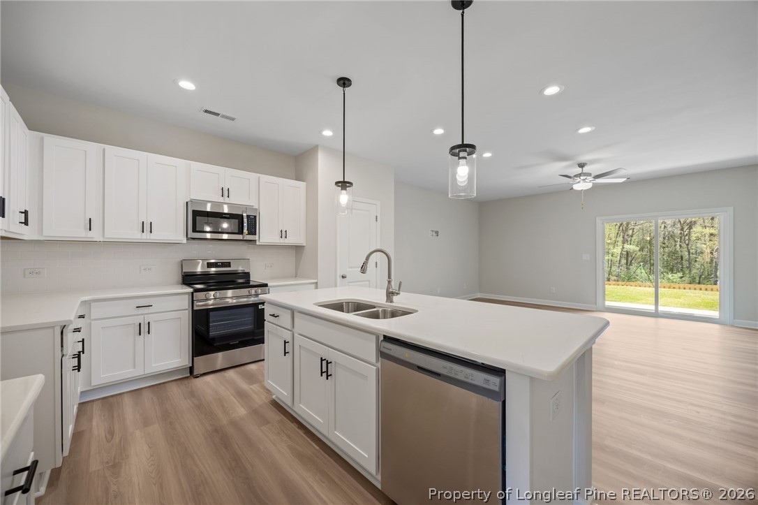 232 Elijah Way, Unit 8 Vass, NC 28394 - Photo 7 of 41 a kitchen with stainless steel appliances granite countertop a sink a stove and a wooden floor