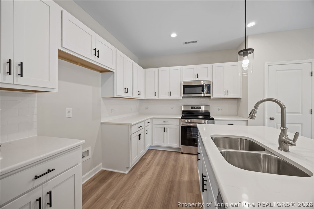 232 Elijah Way, Unit 8 Vass, NC 28394 - Photo 8 of 41 a kitchen with granite countertop a sink stainless steel appliances and white cabinets