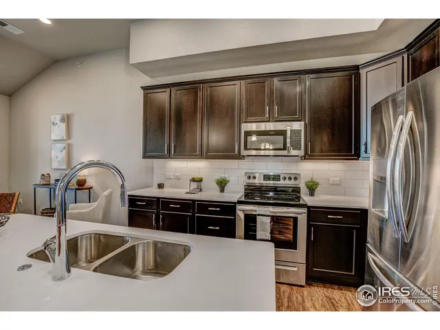 a kitchen with stainless steel appliances granite countertop a sink a stove and refrigerator