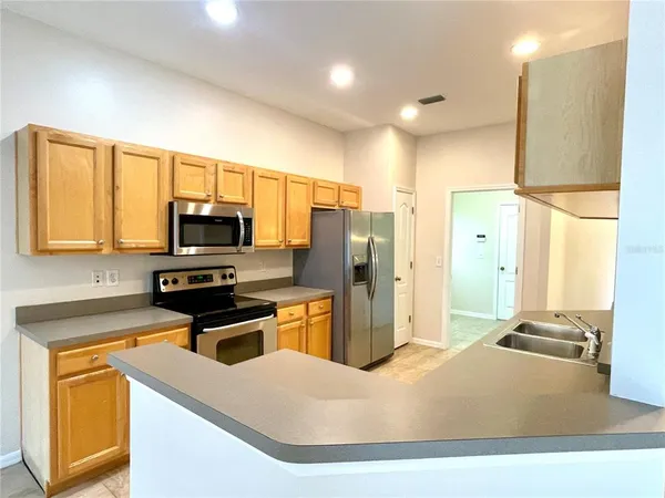 a kitchen with stainless steel appliances a stove a refrigerator a sink a stove white cabinets and wooden floor