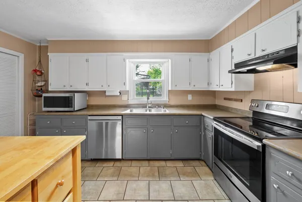a kitchen with kitchen island granite countertop a sink cabinets and stainless steel appliances