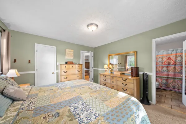 a bedroom with a bed and dresser with mirror
