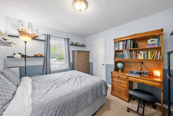 a bedroom with a bed window and a chair