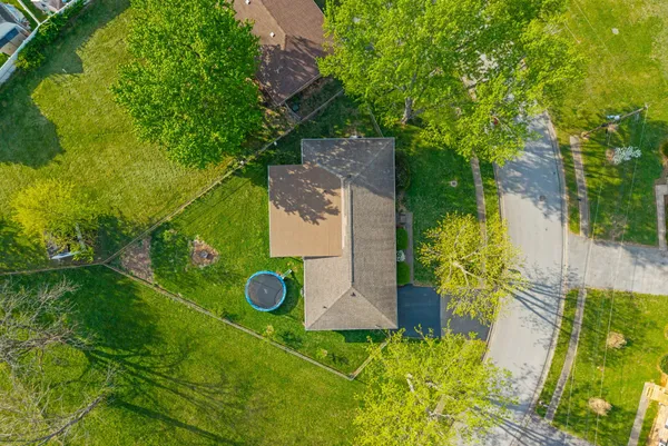 an aerial view of a house with a yard and trees all around