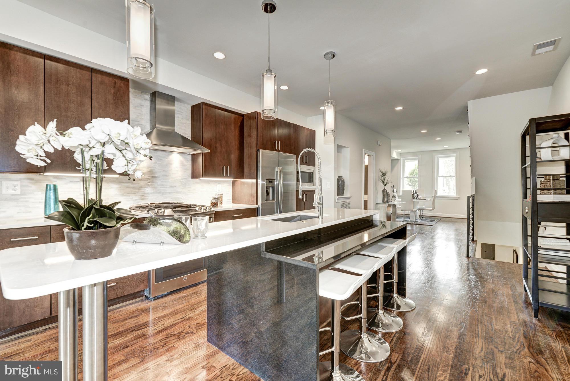 536 14th Street Southeast Washington, DC 20003 - Photo 5 of 25 a kitchen with stainless steel appliances kitchen island granite countertop a table chairs in it and wooden floors