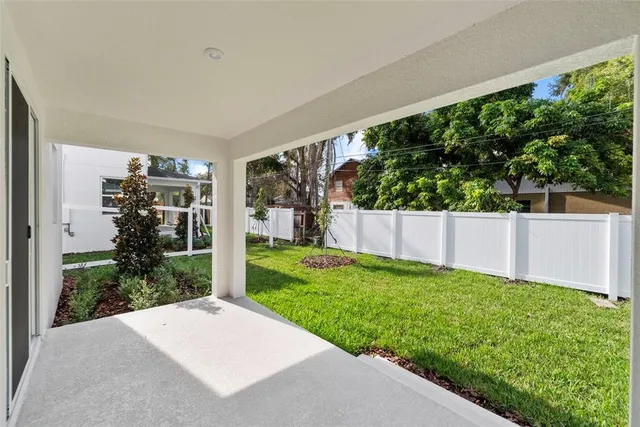 a view of a white house with a big yard potted plants and large tree