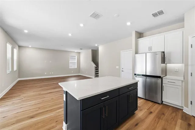 a kitchen with a refrigerator a sink and wooden floor