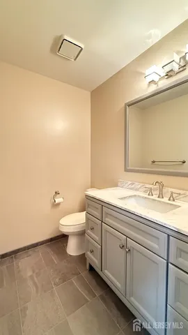 a bathroom with a granite countertop toilet sink and mirror