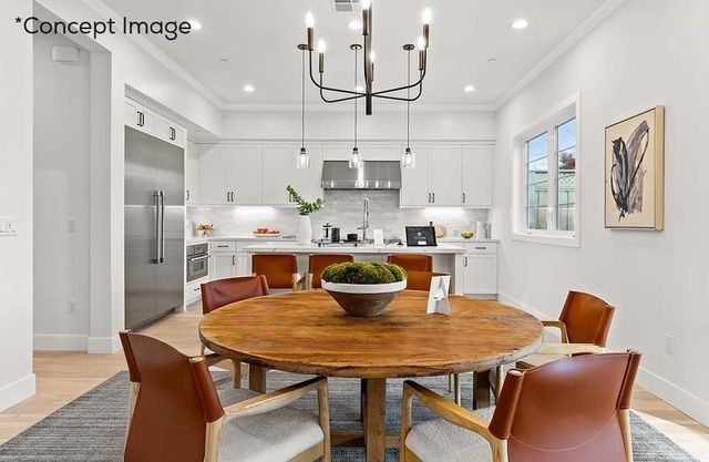 a dining room with stainless steel appliances kitchen island a table chairs and a refrigerator