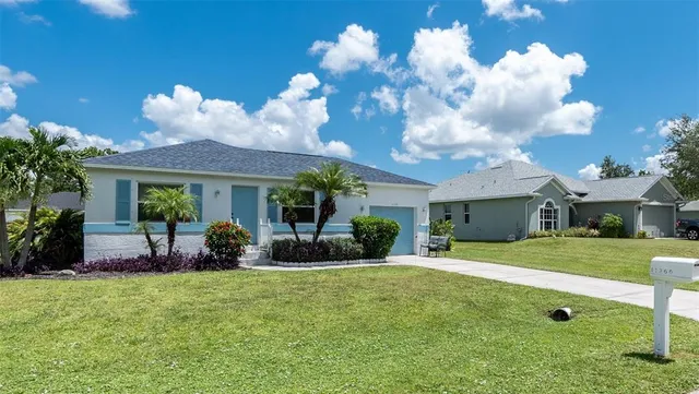 a view of a house with a yard and a large tree