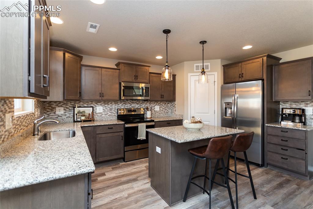 7751 Berwyn Loop Peyton, CO 80831 - Photo 20 of 50 a kitchen with stainless steel appliances granite countertop a table chairs sink refrigerator and microwave