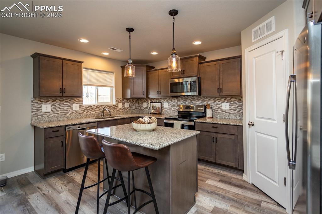 7751 Berwyn Loop Peyton, CO 80831 - Photo 23 of 50 a kitchen with stainless steel appliances granite countertop a stove a sink a refrigerator a center island and a cabinets