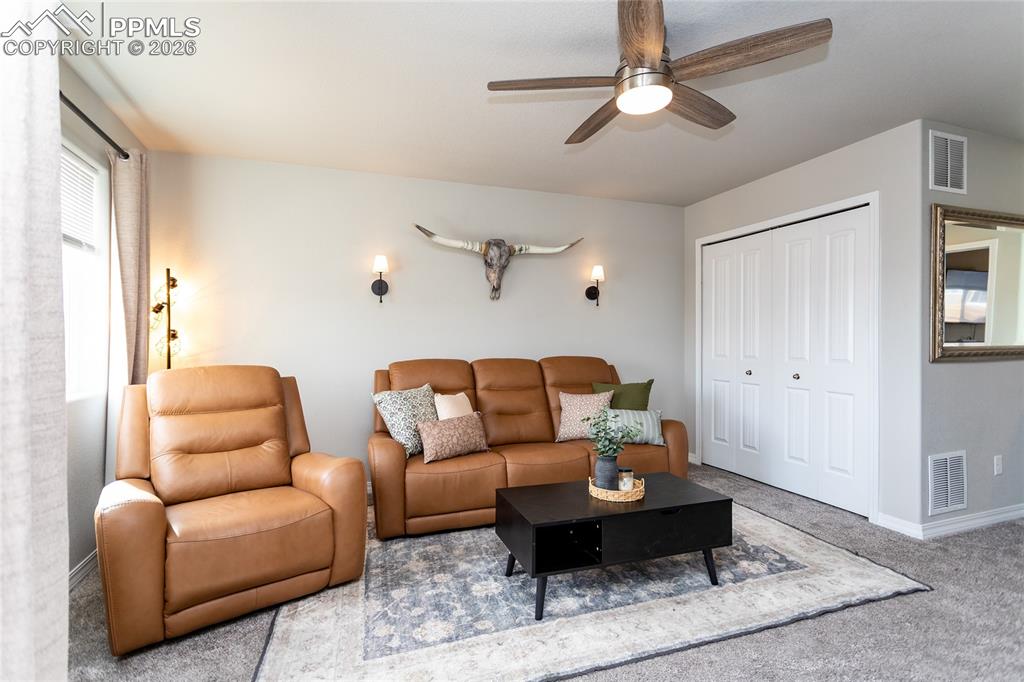7751 Berwyn Loop Peyton, CO 80831 - Photo 33 of 50 a living room with furniture a ceiling fan and a rug