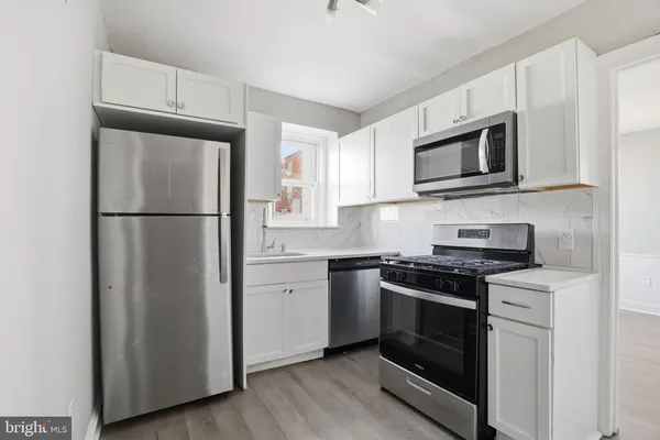 a kitchen with cabinets stainless steel appliances and wooden floor