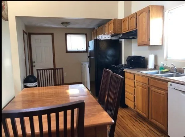 a kitchen with stainless steel appliances wooden floors wooden cabinets a sink and a refrigerator