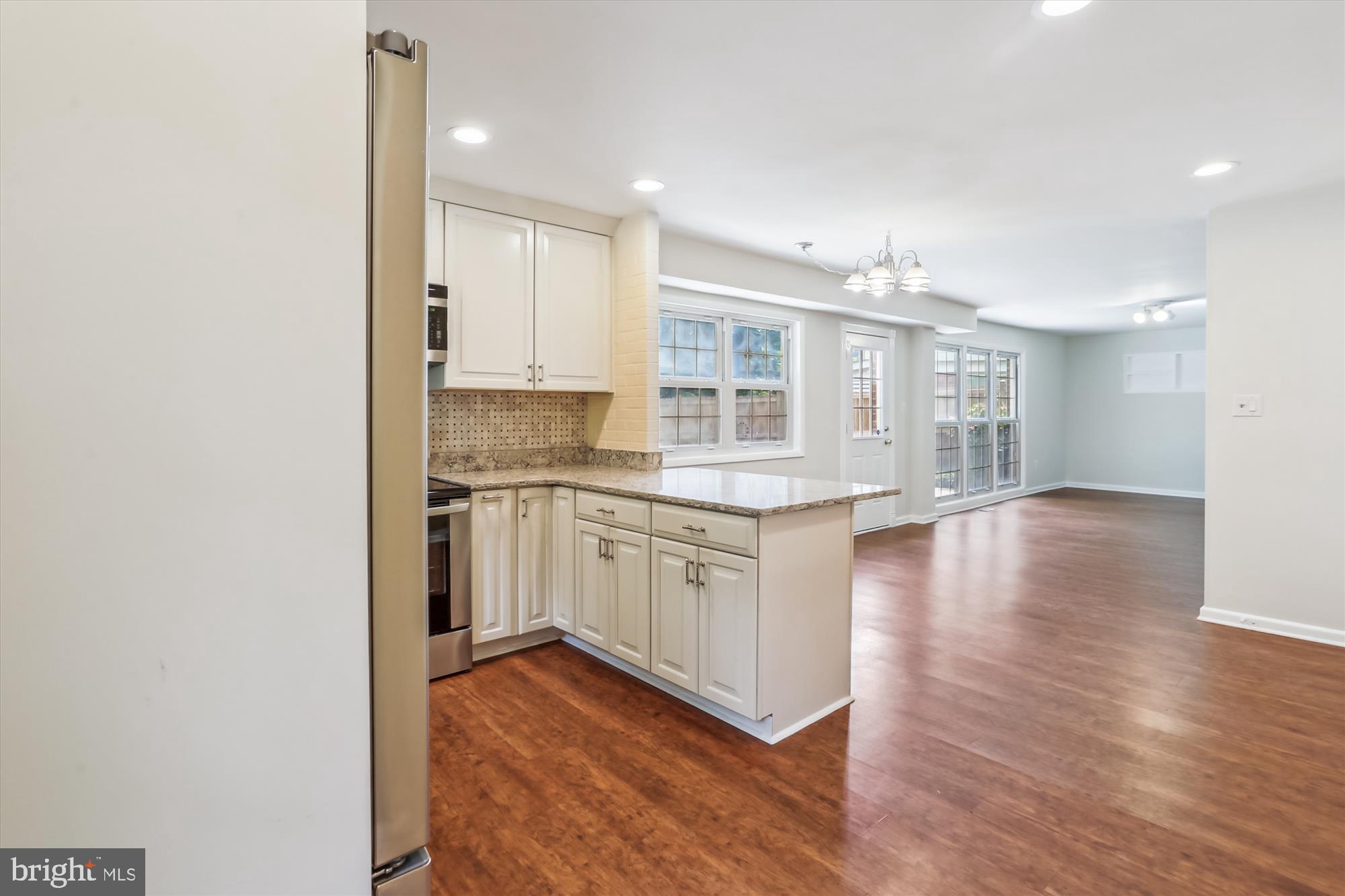 3909 Woodlawn Road Chevy Chase, MD 20815 - Photo 16 of 54 a kitchen with granite countertop white cabinets and wooden floor