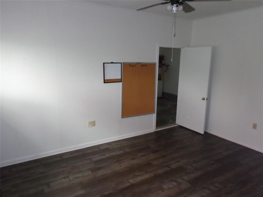 612 South Files Street Itasca, TX 76055 - Photo 9 of 30 Unfurnished room featuring dark wood-type flooring and a ceiling fan