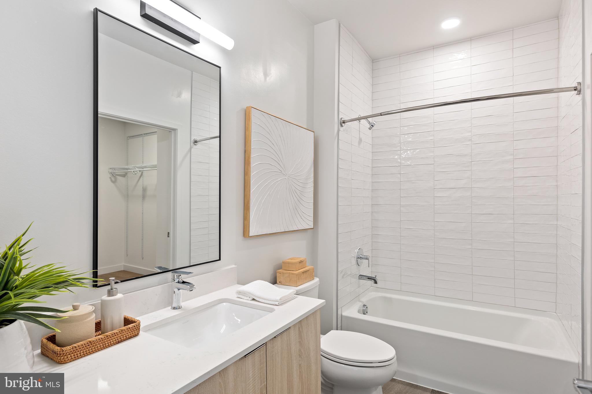 7175 12th Street Northwest, Unit 405 Washington, DC 20012 - Photo 13 of 63 a bathroom with a granite countertop sink toilet a large mirror a shower and a bathtub