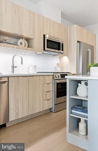 a large kitchen with stainless steel appliances a stove a sink dishwasher a microwave oven with cabinets and wooden floor