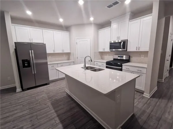 a kitchen with kitchen island a sink stove refrigerator and microwave