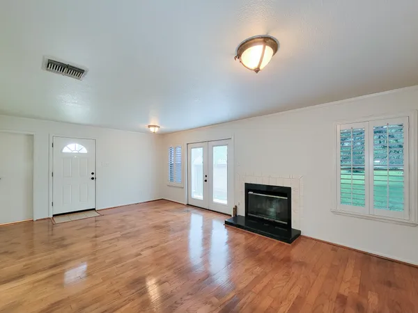 an empty room with wooden floor fireplace and windows
