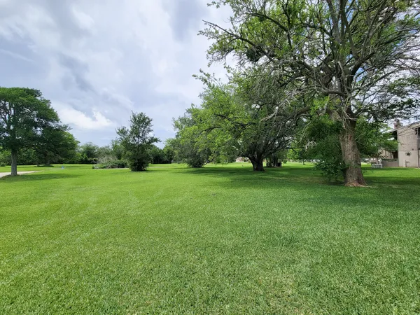 a view of grassy field with benches and trees all around