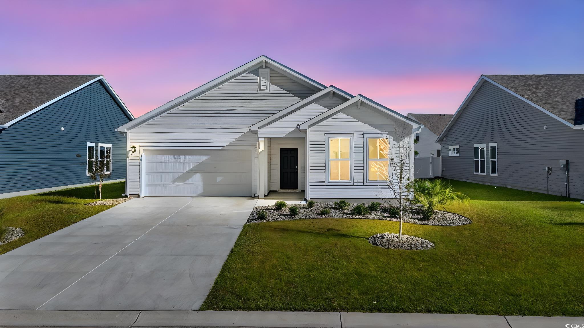 View of front of home featuring concrete driveway, a front lawn, and an attached garage