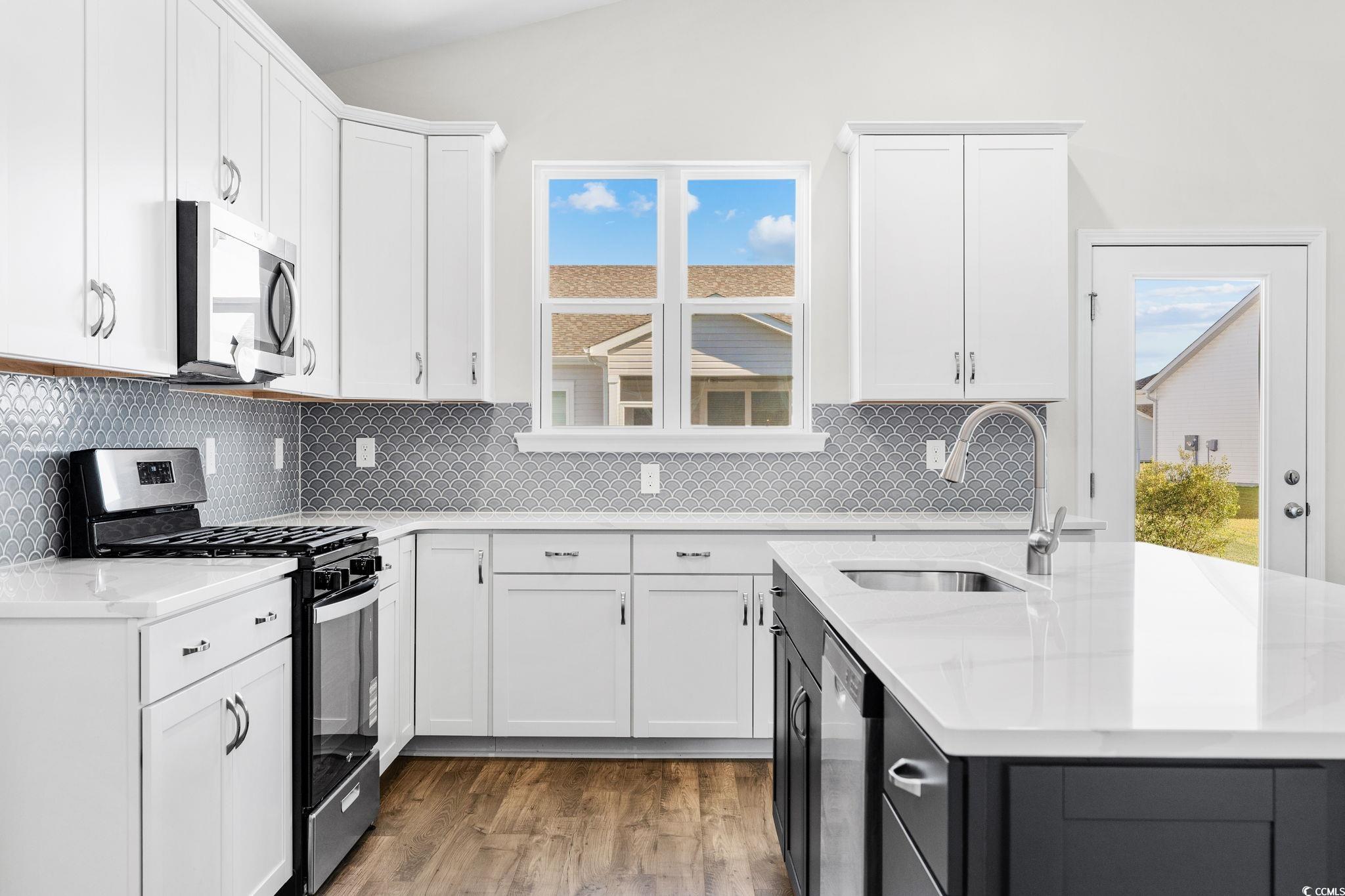 453 Kapalua Loop Little River, SC 29566 - Photo 7 of 27 Kitchen with stainless steel appliances, white cabinets, decorative backsplash, and vaulted ceiling