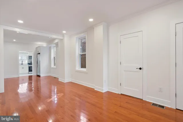a view of an empty room with wooden floor and a window