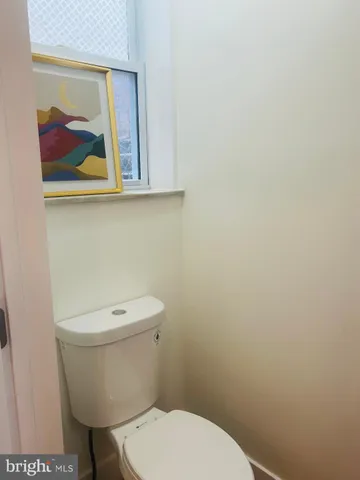 a white toilet sitting next to a white wall