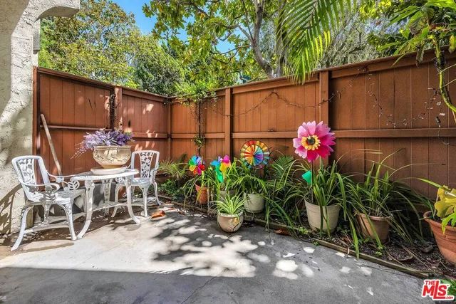 a backyard of a house with table and chairs potted plants and a barbeque