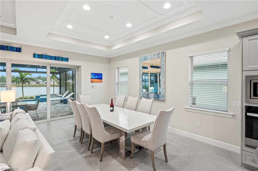 8795 Calypso Court Naples, FL 34113 - Photo 11 of 49 a view of a dining room with furniture large windows and wooden floor