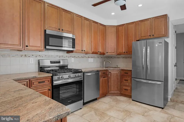 a kitchen with stainless steel appliances granite countertop a stove top oven a refrigerator and a sink with granite countertops