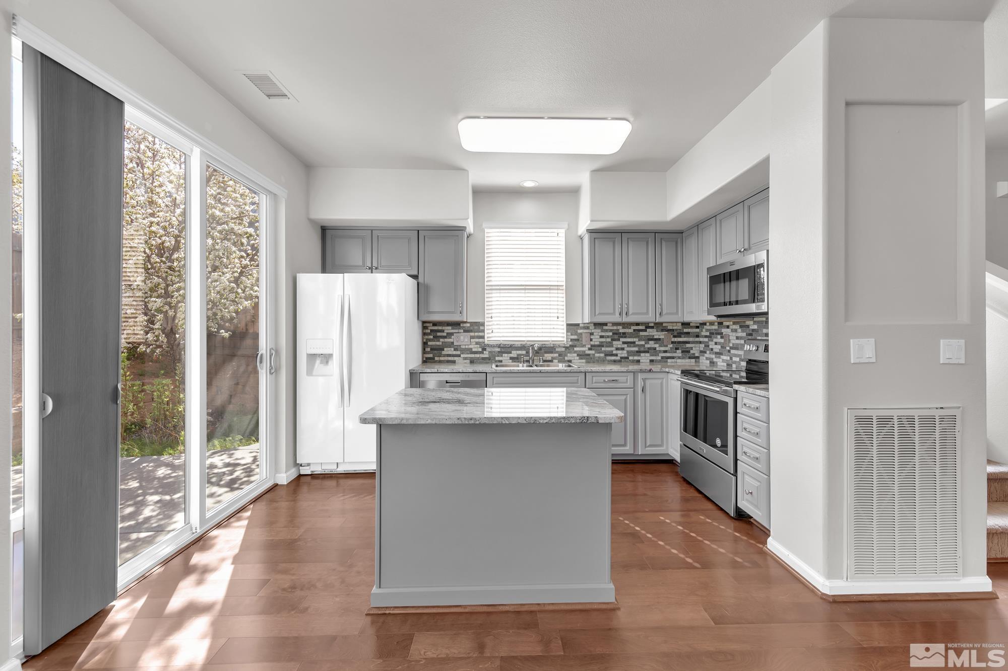 9266 Running Dog Circle Reno, NV 89506 - Photo 7 of 35 a kitchen with stainless steel appliances a stove a sink dishwasher a refrigerator white cabinets and wooden floor
