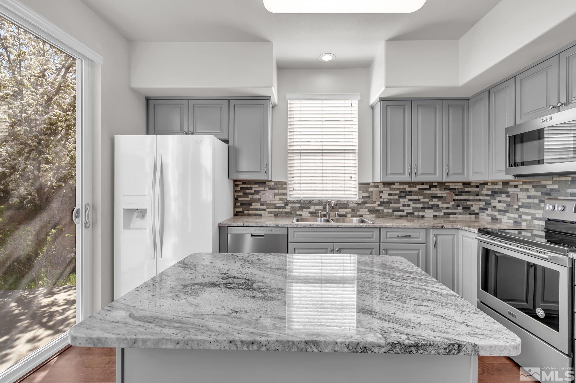 9266 Running Dog Circle Reno, NV 89506 - Photo 9 of 35 a kitchen with granite countertop a refrigerator stove and sink