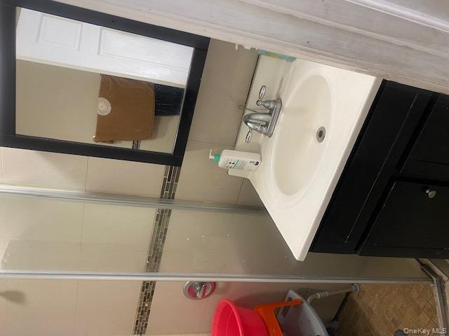 91-07 139th Street Queens, NY 11435 - Photo 10 of 12 a bathroom with a sink a mirror and a toilet