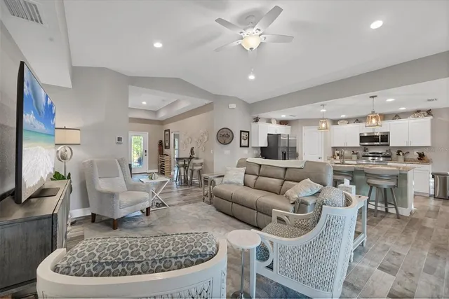 a living room with furniture a rug kitchen view and a chandelier