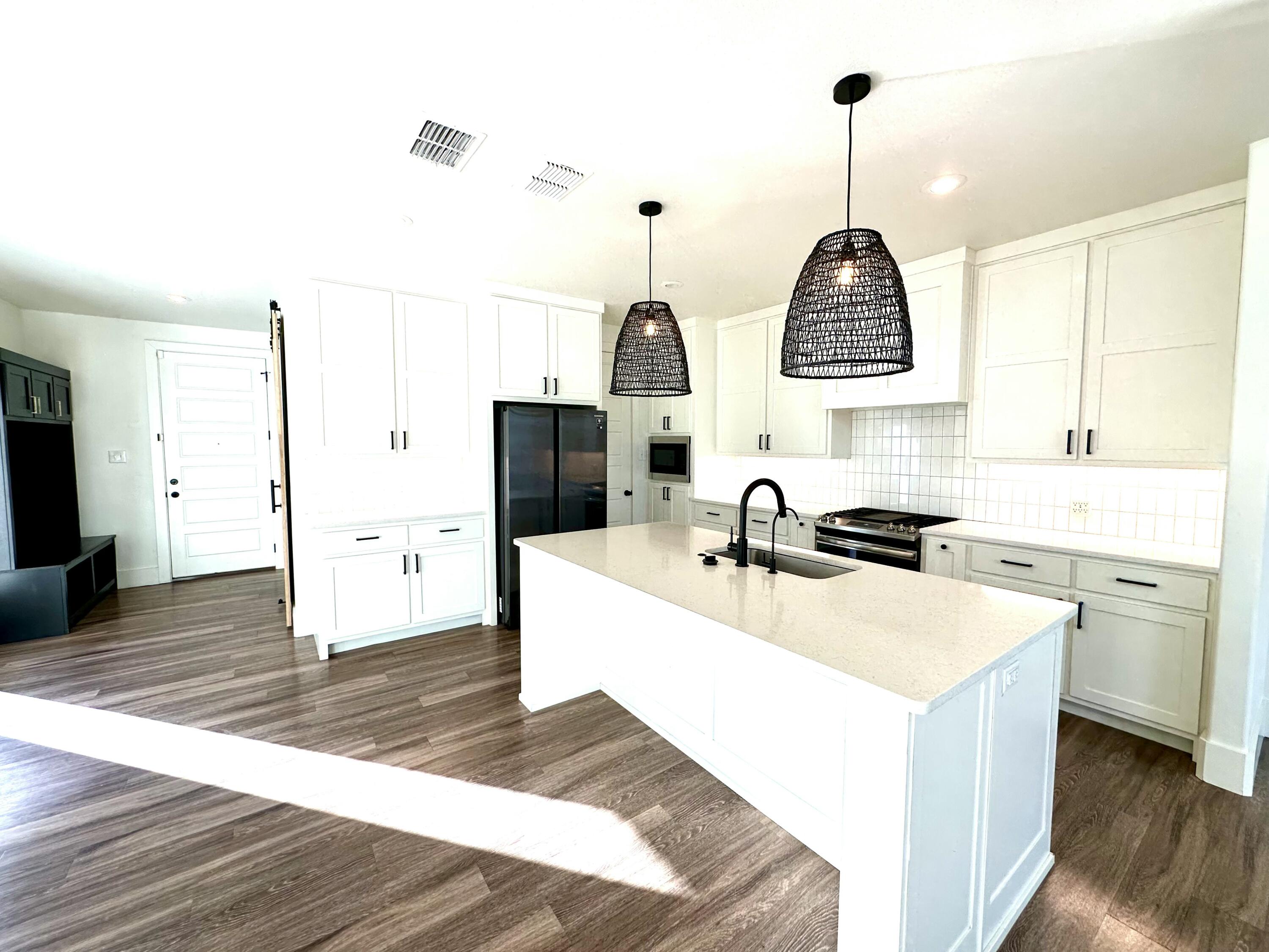 4816 7th Street Lubbock, TX 79416 - Photo 7 of 10 a kitchen with stainless steel appliances a sink stove and wooden floor
