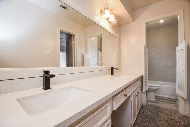 a bathroom with a sink a toilet a mirror and shower