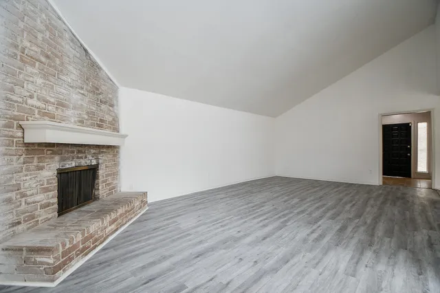 a view of empty room with wooden floor and fireplace