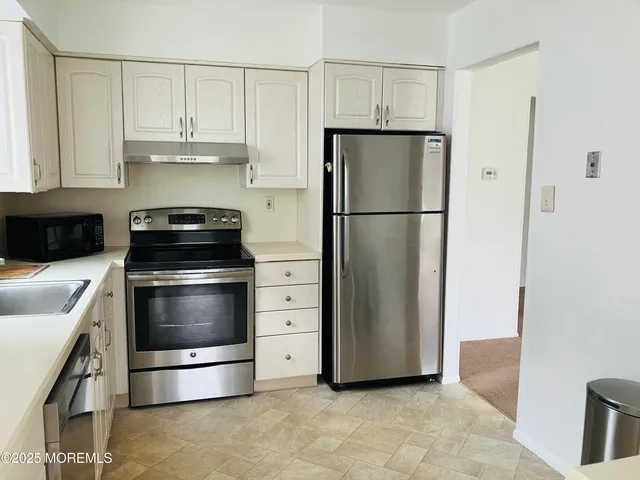 a kitchen with refrigerator a stove a microwave and cabinets