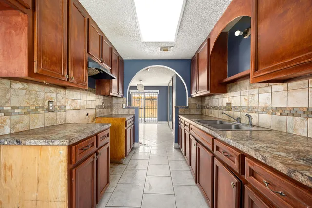 a kitchen with stainless steel appliances granite countertop a sink a stove and a wooden cabinets