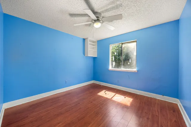 a view of empty room with wooden floor and fan