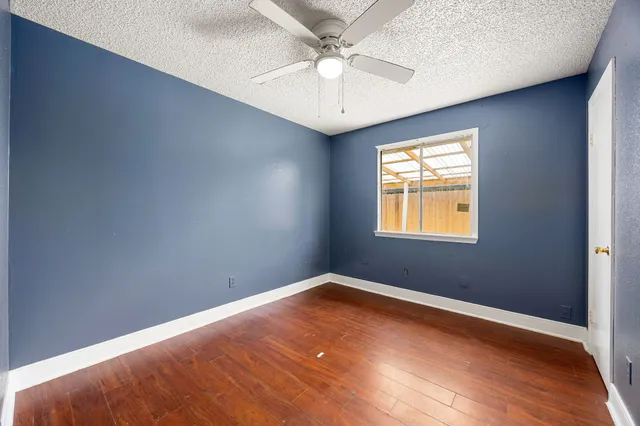 an empty room with windows and fan
