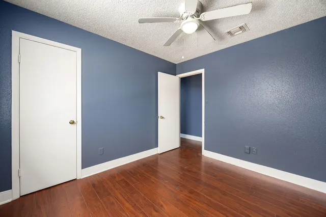 an empty room with wooden floor fan and windows
